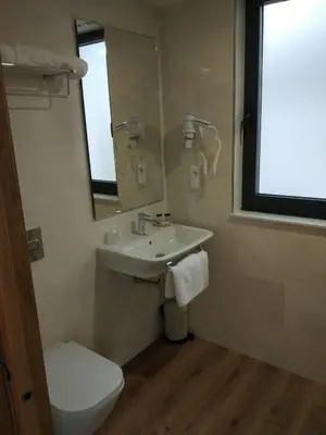 a bathroom with a sink and a toilet and a mirror at Casona da Ponte in Portomarin