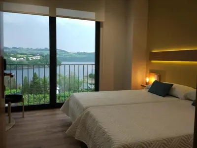 a bedroom with a large bed and a large window at Casona da Ponte in Portomarin