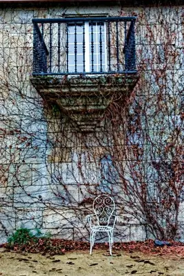 a white chair sitting in front of a building with a window at Casa do Comediante in Cerdeira
