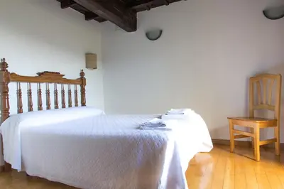 a bedroom with a white bed and a wooden chair at Casa do Comediante in Cerdeira