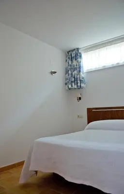 a white bedroom with a bed and a window at Casa do Comediante in Cerdeira