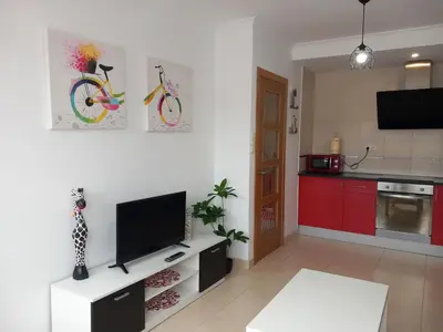 a living room with a tv and a kitchen at Playa Caosa in San Ciprián