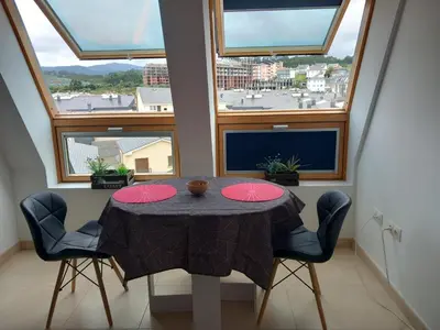 a dining room with a table and some windows at Playa Caosa in San Ciprián