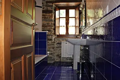 a bathroom with a sink and a tub and a window at Apartamentos El Llago in Boal