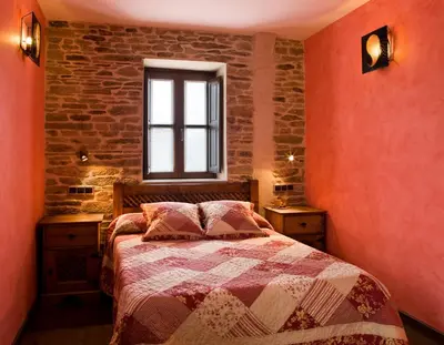 a bedroom with a bed and a brick wall at Hostal Raices in Puebla de Sanabria