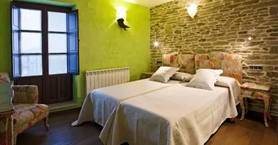 a bedroom with a bed and a brick wall at Hostal Raices in Puebla de Sanabria