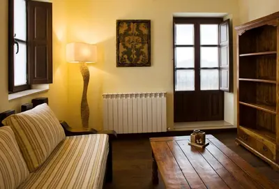 a living room with a couch and a table and a lamp at Hostal Raices in Puebla de Sanabria