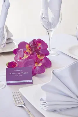 a table with white plates and a purple flower on it at Hotel Mar de Plata in Sarria