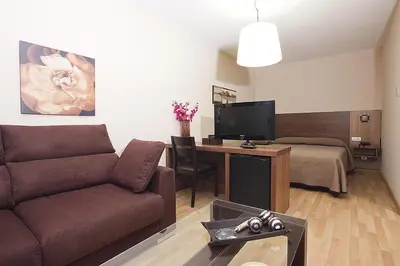 a living room with a couch and a table with a television at Hotel Mar de Plata in Sarria