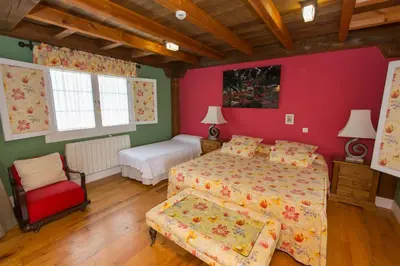 a bedroom with two beds and a red wall at Hotel Rural Casa Xusto in La Caridad