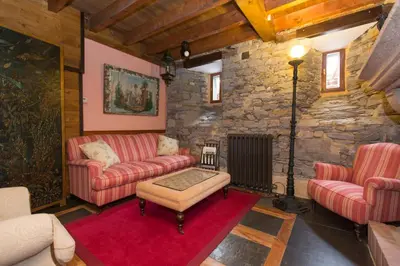 a living room with two couches and a stone wall at Hotel Rural Casa Xusto in La Caridad