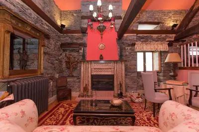 a living room with a fireplace and a red wall at Hotel Rural Casa Xusto in La Caridad