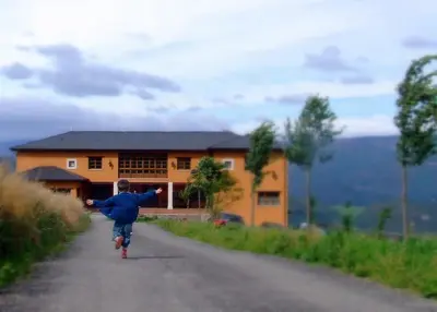 a boy running down a road in front of a house at Hotel Rural Yeguada Albeitar in Villayón