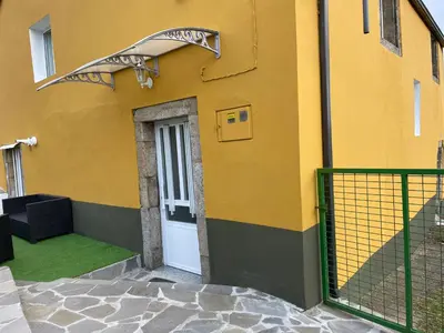 a yellow building with a door and a green fence at Casa Tipica De La Zona con barbacoa y parking in Muras