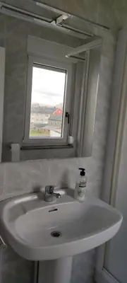 a bathroom sink with a mirror and a window at Xabarin Apartment in Abadín