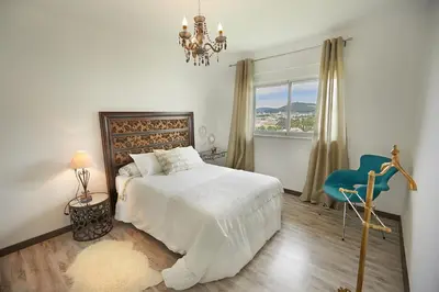 a bedroom with a white bed and a blue chair at Apartamento en Viveiro in Viveiro