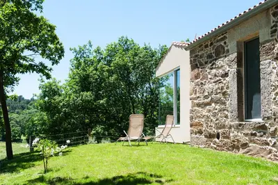 a stone house with two chairs in the yard at Casa das Landras in Chantada