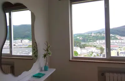 a bathroom with a mirror and two windows at Piso con excelentes vistas in Viveiro