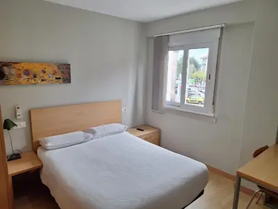 a white bedroom with a bed and a window at PR Blanco in Santiago de Compostela