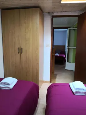 two beds in a room with purple sheets at Casa Carlán in Melide