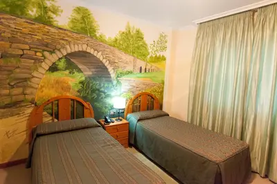 a bedroom with two beds and a wall with a bridge at Hostal Restaurante Terra Chá in Villalba
