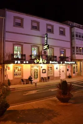 a building with a sign on it at night at Hostal-Restaurante Paris in Forcarei
