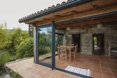 a glass extension of a house with a patio at O Curralino in Vilacoba