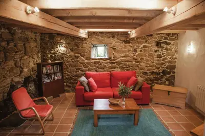 a living room with a red couch and a table at O Curralino in Vilacoba