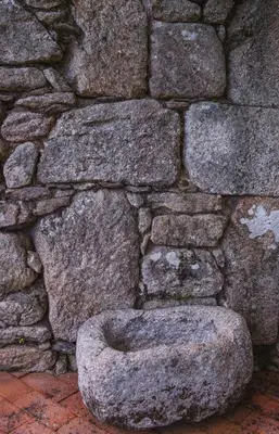a stone toilet in front of a stone wall at O Curralino in Vilacoba