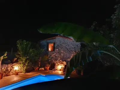 a stone house with a swimming pool at night at casa cristimil -san amaro in Salamonde