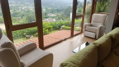a living room with two chairs and a large window at Casa de Sabela in Culleredo