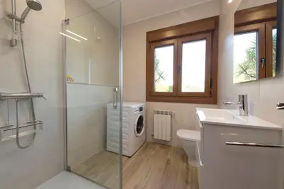 a bathroom with a sink and a washing machine at Casa de Sabela in Culleredo