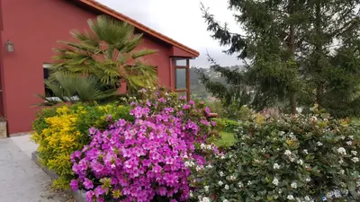 a garden of flowers in front of a red building at Casa de Sabela in Culleredo