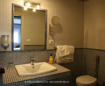 a bathroom with a sink and a toilet and a mirror at Casa Matías in Sarria
