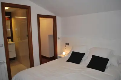 a bedroom with a white bed with two black pillows at Pensión Acibeche in Santiago de Compostela