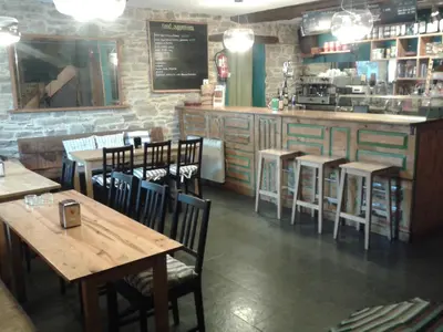 a restaurant with wooden tables and chairs and a counter at El Puente Peregrino in Trabadelo