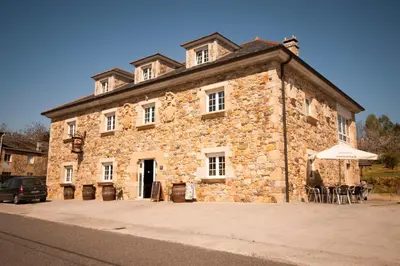 an old stone building with an umbrella in front of it at As Viñas in Viveiro