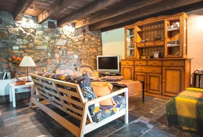 a bedroom with a stone wall with a tv and a crib at Rural Médulas Viviendas de uso turistico 2 y Casas rurales 2 in Las Médulas