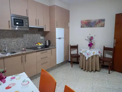 a kitchen with a table and a white refrigerator at Albergue Agarimo in Caldas de Reis