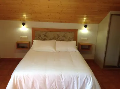 a large white bed in a room with two lights at Alojamiento en entorno rural Los Trobos in Villar de Otero