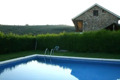 a swimming pool with a house in the background at Alojamiento en entorno rural Los Trobos in Villar de Otero