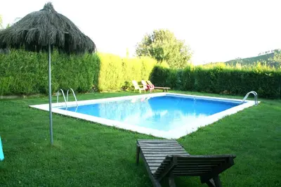 a swimming pool with two chairs and an umbrella at Alojamiento en entorno rural Los Trobos in Villar de Otero