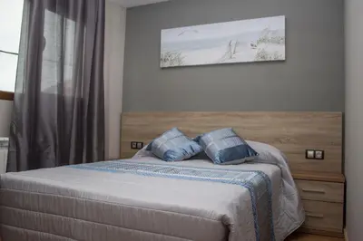 a bedroom with a bed with two blue pillows at O Vendaval Hostal Restaurante in Barreiros