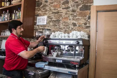 a man standing behind a coffee machine in a bar at O Vendaval Hostal Restaurante in Barreiros