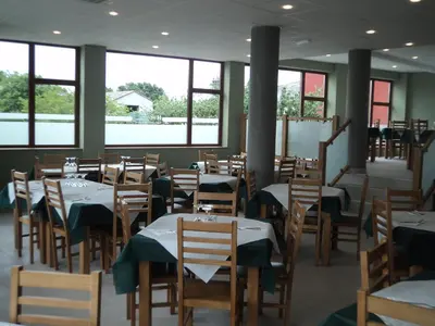a dining room with tables and chairs and windows at O Vendaval Hostal Restaurante in Barreiros