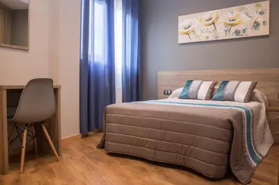 a bedroom with a bed and a desk and a chair at O Vendaval Hostal Restaurante in Barreiros
