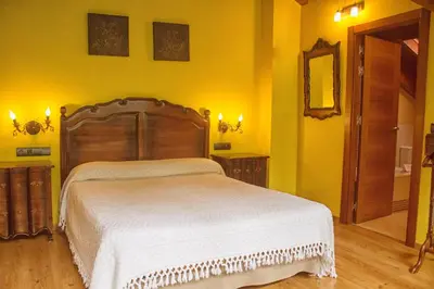 a bedroom with a large bed in a yellow room at Hotel Valle del Silencio in Ponferrada