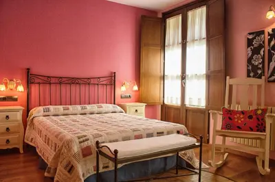 a bedroom with pink walls and a bed and a chair at Hotel Valle del Silencio in Ponferrada