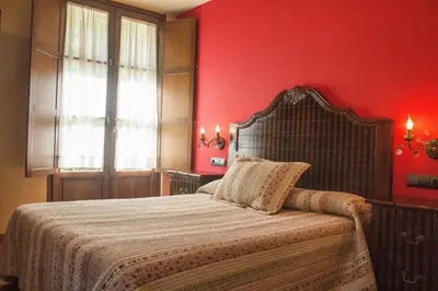 a bedroom with a bed with red walls and a window at Hotel Valle del Silencio in Ponferrada