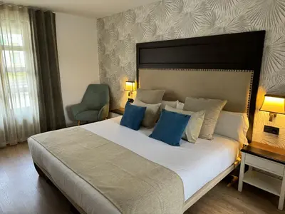 a bedroom with a large white bed with blue pillows at VISTALEGRE Hotel-Spa in Portomarin